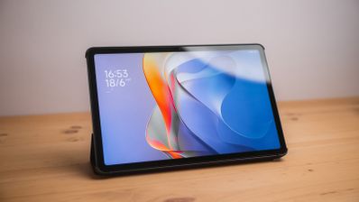Tablet Redmi Pad 2 apoyada sobre una mesa de madera con la pantalla de bloqueo encendida.