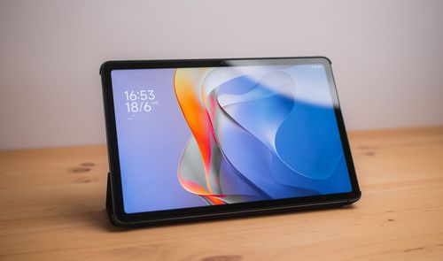 Tablet Redmi Pad 2 apoyada sobre una mesa de madera con la pantalla de bloqueo encendida.