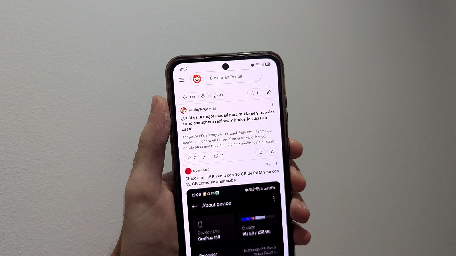 Primer plano de una mano sosteniendo un smartphone que muestra la aplicación de Reddit en pantalla.