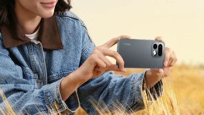 Persona sujetando en horizontal un realme 16 pro de color gris oscuro para tomar una fotografía en un campo de trigo.