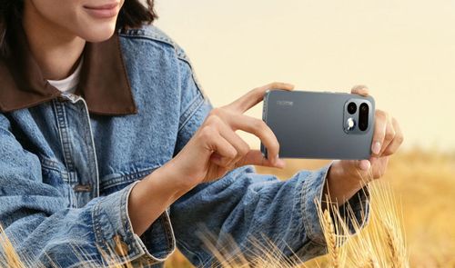 Persona sujetando en horizontal un realme 16 pro de color gris oscuro para tomar una fotografía en un campo de trigo.
