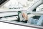 Conductor interactuando con la aplicación Google Maps en un smartphone colocado en el salpicadero de un coche.