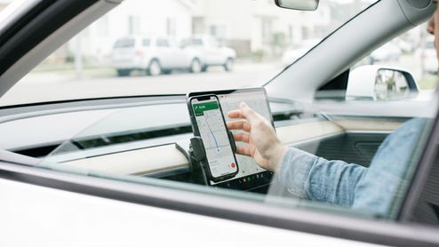 Conductor interactuando con la aplicación Google Maps en un smartphone colocado en el salpicadero de un coche.