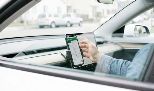Conductor interactuando con la aplicación Google Maps en un smartphone colocado en el salpicadero de un coche.