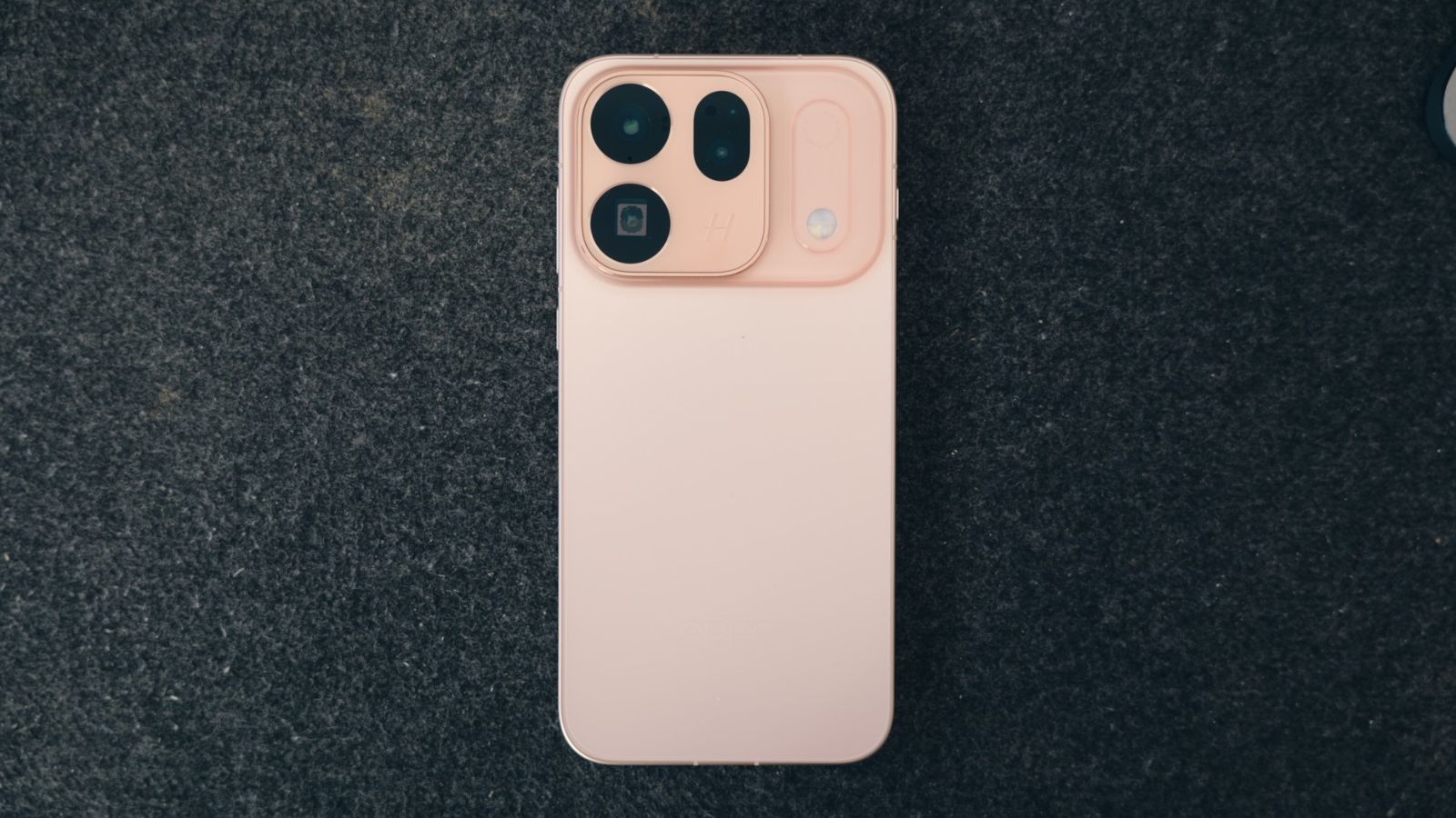 Parte trasera de un teléfono OPPO Find X10 en color rosa pastel con un módulo de cámaras cuadrado y bordes redondeados sobre una superficie oscura.