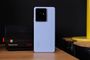 Parte trasera del teléfono móvil realme GT7 en color blanco con módulo de cámaras cuadrado situado junto a una cámara instantánea clásica.