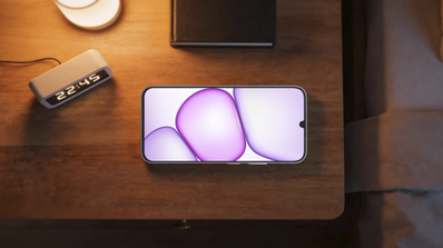 Teléfono móvil realme P4 Lite situado sobre una mesa de noche junto a un despertador digital y una lámpara.