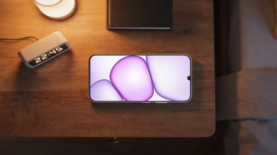 Teléfono móvil realme P4 Lite situado sobre una mesa de noche junto a un despertador digital y una lámpara.