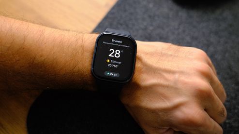 Smartwatch con pantalla rectangular en la muñeca mostrando la aplicación del tiempo con 28 grados.