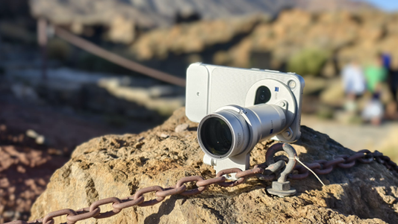 Teléfono vivo X500 Pro Max con una lente telescópica acoplada sobre una roca en un entorno natural.