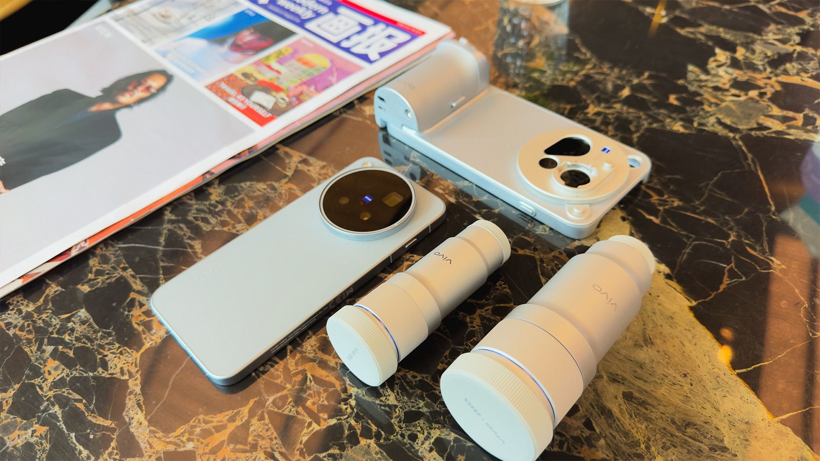 Conjunto de accesorios del kit fotográfico para el vivo-X500 Pro Max sobre una mesa, incluyendo lentes externas y una carcasa con empuñadura.