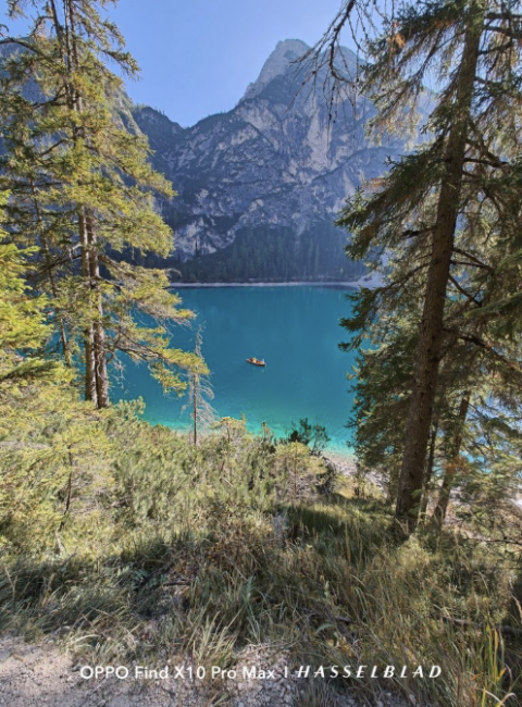 Bote de remos navegando por un lago de aguas turquesas rodeado de coníferas y grandes paredes de roca.