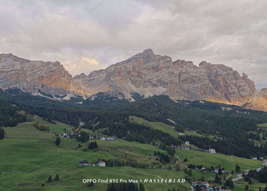 Macizo montañoso de los Dolomitas bajo un cielo nublado con praderas verdes en el valle.