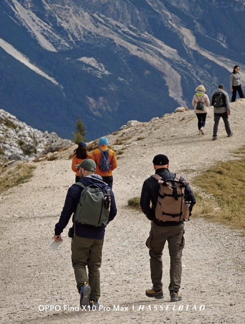 Senderistas con mochilas caminando por un sendero de tierra en la montaña.