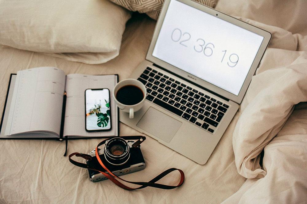 iphone y macbook en la cama con cafe